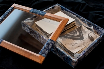 a box with a glass top, collaged with blue origami paper, suminagashi cards and silk inside.